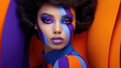 Model with geometric body paint in purple and blue hues on an orange backdrop.