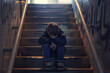 Bullying concept. A depressed boy sits alone on the stairs with space for text or inscriptions
