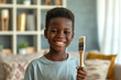 Happy young African American boy confidently holding a painting brush during home renovation
