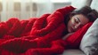 A young woman peacefully sleeps under a bright red blanket