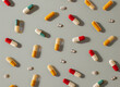 Various capsules and tablets arranged in a random pattern on a grey background