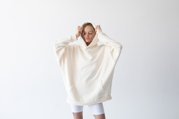 Wall Mural - Beautiful blonde woman posing in white hoodie and leggings posing against white background