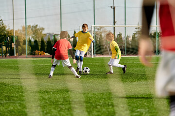 Wall Mural - A group of young children, full of energy and enthusiasm, playing an intense game of soccer on a grassy field. They are kicking, running, and passing the ball, displaying teamwork and sportsmanship.