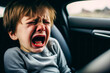 A little boy sits in the back seat of a car and roars, uncontrollably showing his dislike of traveling. He doesn't like riding 