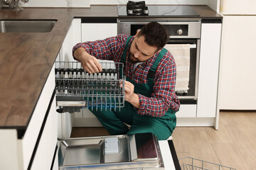 Poster - Serviceman repairing dishwasher cutlery rack in kitchen