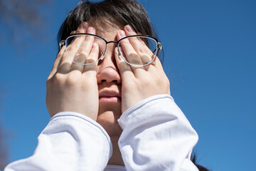 Wall Mural - Conceptual portrait of a woman in eyeglasses. Young attractive woman covering her face with a her hands	