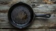 A vintage cast iron skillet, its seasoned surface rich with history, set against a rustic wooden backdrop, emphasizing durability and timeless appeal low texture