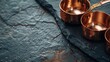 A set of copper measuring cups, their gleaming surfaces reflected against a dark stone countertop, blending elegance with precision in baking and cooking low texture