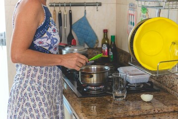 Closeup shot of a young female in a dress making food on the stove