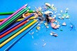 Closeup of stack of colorful wooden pencils and sharpened scraps isolated on blue background