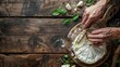 Hands cutting a soft brie cheese on a rustic wooden table
