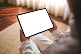 Fototapeta  - Mockup image of a woman holding digital tablet with blank desktop screen while sitting on a sofa at home