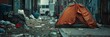 Homeless person's tent pitched on a sidewalk, surrounded by trash and discarded items