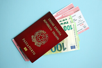 Wall Mural - Italian passport with money and airline tickets on blue background close up. Tourism and travel concept