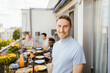 © Maskot - Portrait of smiling man with multiracial friends celebrating during dinner party in balcony