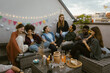 © Maskot - Group of male and female friends sitting and talking with each other at party in decorated balcony