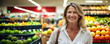 Beautiful middle-aged woman smiles while shopping at the supermarket with her trolley in the fruit section