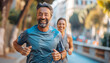 Handsome middle-aged smiling grey haired man jogging with beautiful wife by city street, enjoying a sunny day together. Sporty active people, healthy lifestyle concept training image.