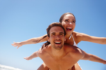 Wall Mural - Couple, piggyback and freedom on beach with happiness for bonding, summer vacation and travel adventure. Man, woman and love by ocean with mockup space for getaway, healthy relationship and blue sky