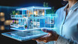 A design engineer holds a digital tablet on which a three-dimensional holographic projection of a modern house is displayed. Development of a house construction project