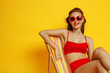 Studio photo of a beautiful girl in a red swimsuit and sunglasse