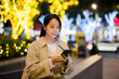 Woman hold with smart phone in Taipei city at evening time