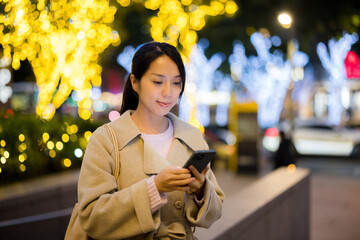 Poster - Woman hold with smart phone in Taipei city at evening time