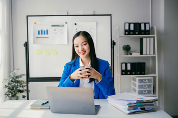 Poster - A woman in a blue suit is sitting at a desk with a laptop and a cup of coffee