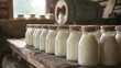 Vintage style image of milk bottles lined up on a rustic wooden shelf, implying freshness and local production