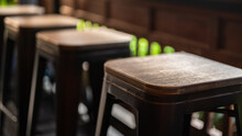 Group Of Tall Wooden And Iron Retro Style Seats At The Coffee Counter Bar. Furniture Object Photo, Close-up And Selective Focus At The Seat's Part.
