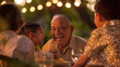 © Armin - An elderly gentleman laughing with his grandson during an outdoor family dinner