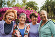 Group of happy diverse senior women hugging each other at city park while smiling on camera - Multiracial female community