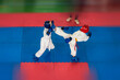 Children's fight of taekwondo athletes on a blue-red tatami with art motion blur.
