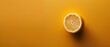   A lemon, halved, sits atop a yellow table Nearby rests a single sliced lemon against a similar hue background