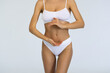 Dieting. Cropped image of slim healthy female body, breast, belly over grey studio background.