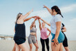© okrasiuk - Happy fitness class giving high five after completing workout on beach. Multi aged women motivated after session together, engaged in team building, join hands for shared goal or success at training.