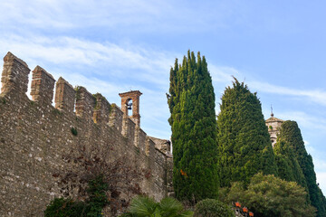 Poster - Crenellated walls with bell towers of the church of Santa Maria Maggiore in the medieval village on the shore of Lake Garda, Sirmione, Brescia, Lombardy, Italy