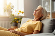 Cheerful sleepy blonde older lady lying on couch