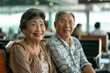 Happy elderly Asian couple seated at the airport
