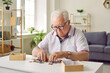 © Studio Romantic - Portrait of a senior elderly sad gray-haired man collecting wooden jigsaw puzzles game at home sitting at the table. Memory training for dementia prevention and retirement leisure concept.