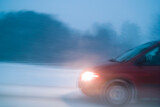 Fototapeta Dmuchawce - Car driving through winter snow storm