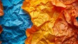   A tight shot of crinkled paper displaying varied hues of blue, yellow, and orange
