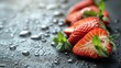   A group of strawberries sits atop a table, its surface dotted with water drops against a black background