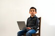 © dobok - A child boy sitting on a chair with a laptop in his lap isolated on white background
