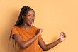 suspicious black woman raising arms and celebrating in beige background. celebration, positive, success concept.