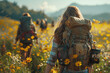 Backpackers in casual hiking attire stand amidst a sea of yellow flowers, mountains in the distance, under a vast blue sky