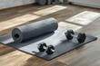 Rolled up mat placed on floor near black dumbbells and yoga block while being prepared for workout in light room