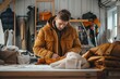 Side view of crop anonymous male fashion designer in warm jacket while standing at table with garments and working on clothes in modern design shop in lapland
