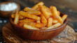 A bowl of french fries sits on a wooden table
