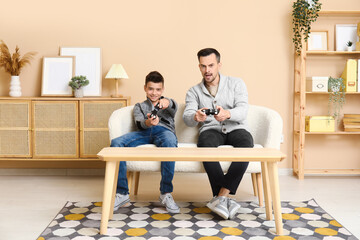 Poster - Father and his little son playing video games on sofa at home